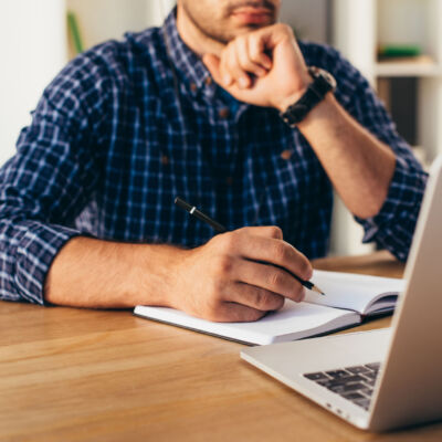 cropped shot of businessman with notebook taking part in webinar