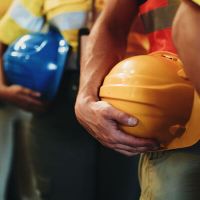 Group, line and hands with helmet in warehouse for freight safety regulations or shipping cargo. People, supplier team or distributor in row with hard hat for maintenance or supply chain service