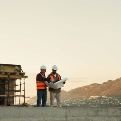 Team, blueprint and engineer at construction site for planning, development review or layout. Floor plan, men and paperwork for architecture design, building discussion or mockup space outdoor